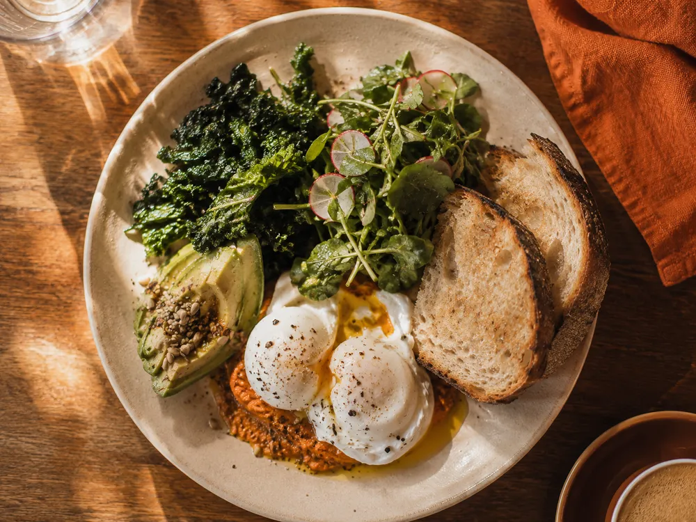 Signature brunch plate with poached eggs, avocado and sourdough toast in morning sun.