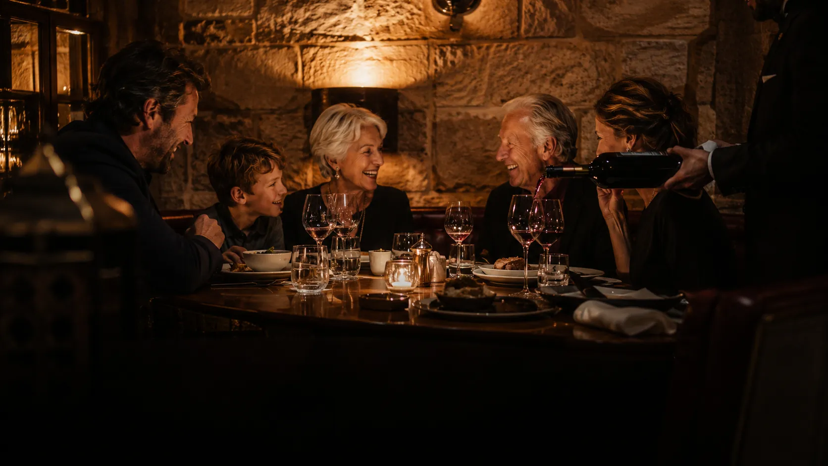 Candlelit dining room mid-service, guests gathered at the arrival course