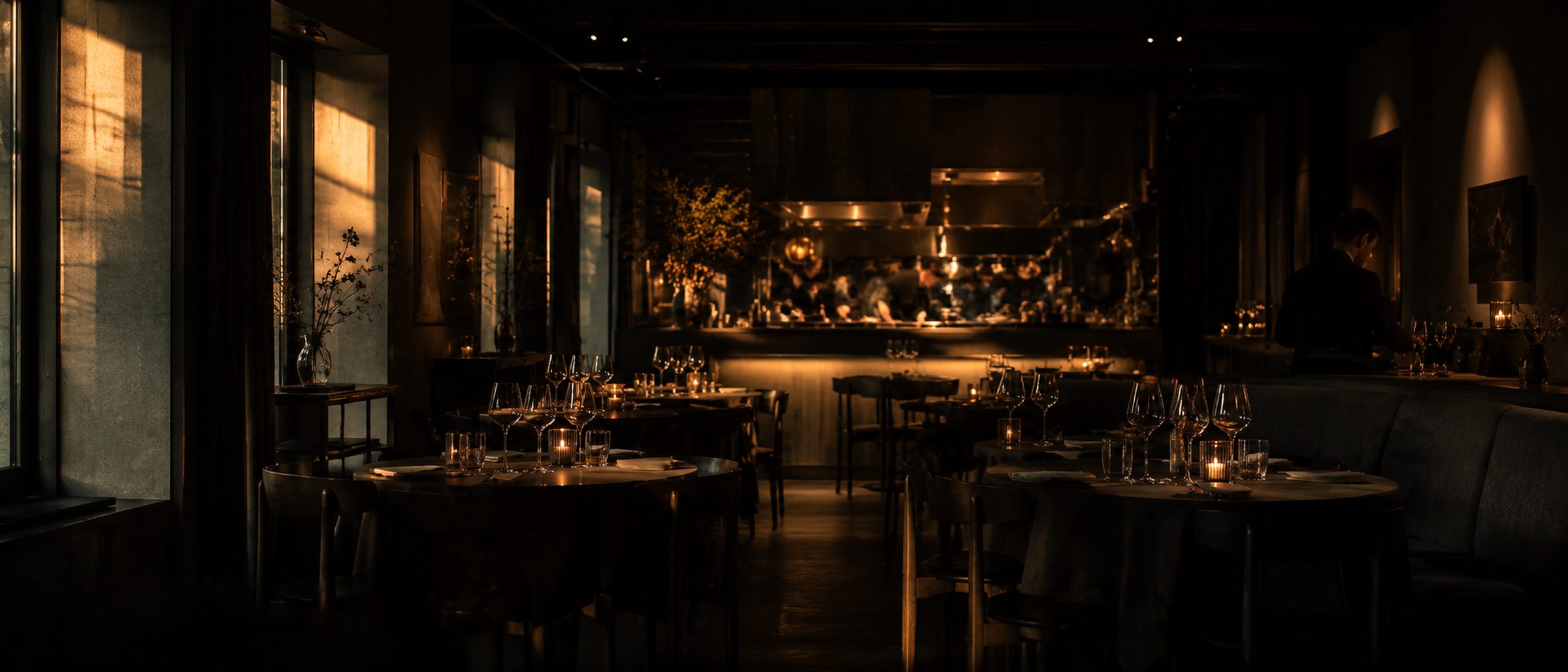 The dining room at golden hour with candles lit and the pass glowing.