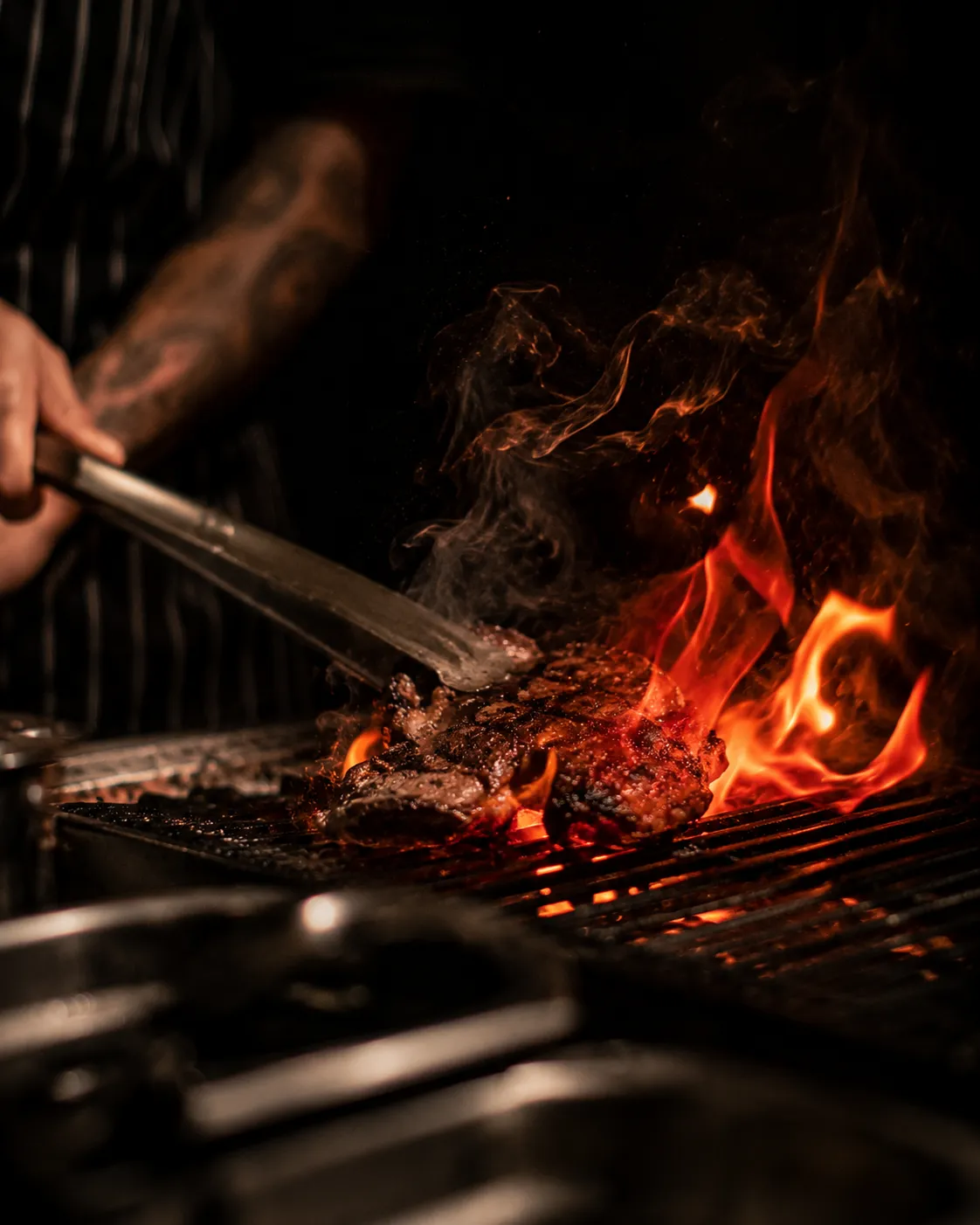 Chef or founder at the pass mid-action, face half-shadow, hands lit, visceral and real