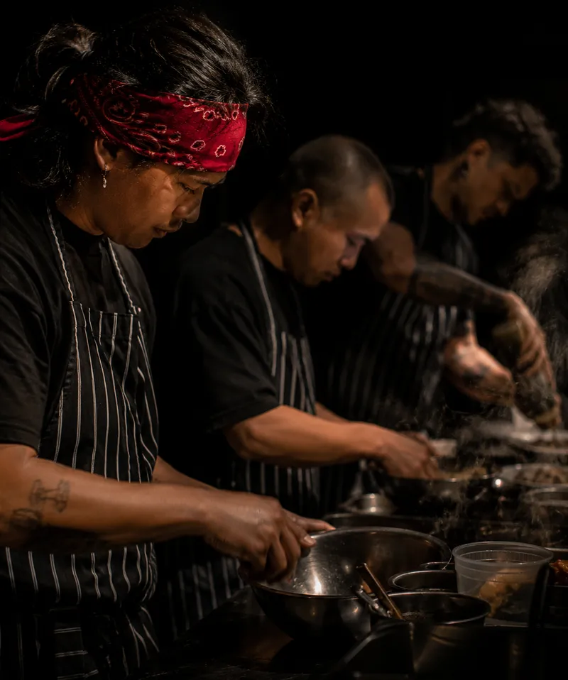 Chef or founder mid-action in kitchen, hands on the work, looking down, visceral and real